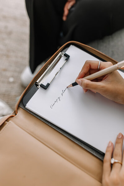 Close-up of a therapist writing on a notepad during a business branding photoshoot, highlighting professionalism and organisation for their practice.