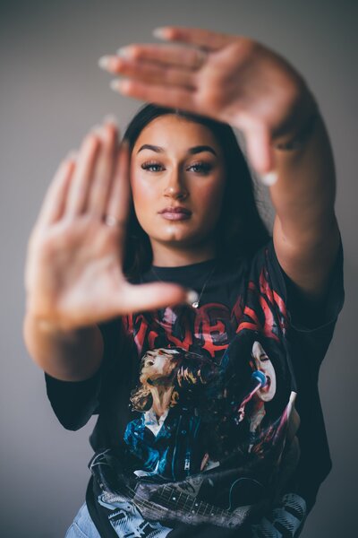 A woman wearing a t - shirt making a hand gesture, captured by a Shreveport senior photographer Britt Elizabeth.