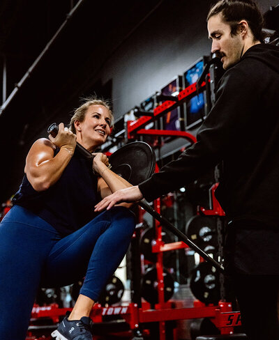 A woman lifts weights with a trainer during her session at Kula Sports Performance.