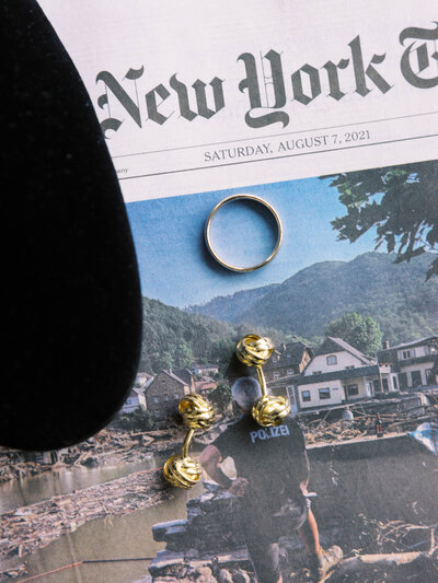 Flatlay of the grooms wedding band and cufflinks on newspaper