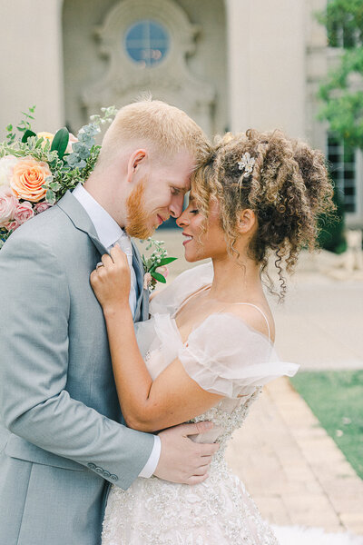 Luxury wedding at The Olana in Hickory Creek, Texas, with the couple sharing a romantic moment against the estate’s grand architecture and manicured gardens.