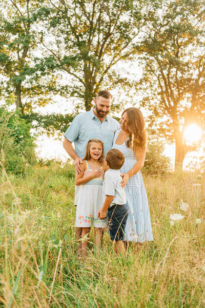 Family of three standing in front of a Christmas tree at sunset