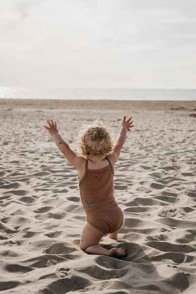 Blij kindje op het strand in Noordwijk bij zonsondergang.