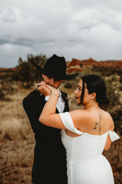 groom kisses brides hand at their ranch wedding in colorado