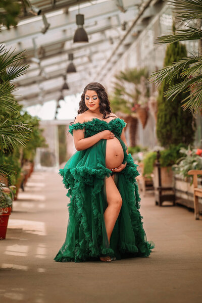 Pretty momma posing in flowy green maternity dress posing at the Denver Botanical Gardens.
