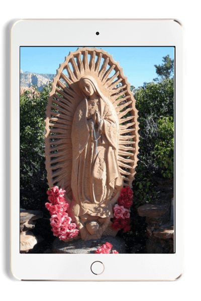 Ipad with image of tan  Mother Mary statue in a garden with pink flowers