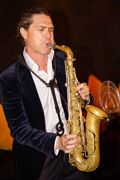 Live saxophone player in velvet blazer performing at a luxury indoor event or wedding reception.