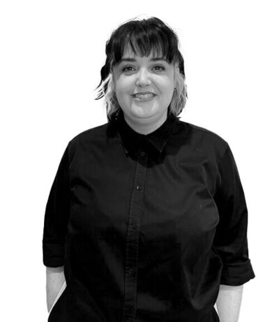 Salon Co-Ordinator with short dark hair and blonde highlights, wearing a black button-up shirt, exuding confidence and a friendly demeanour.