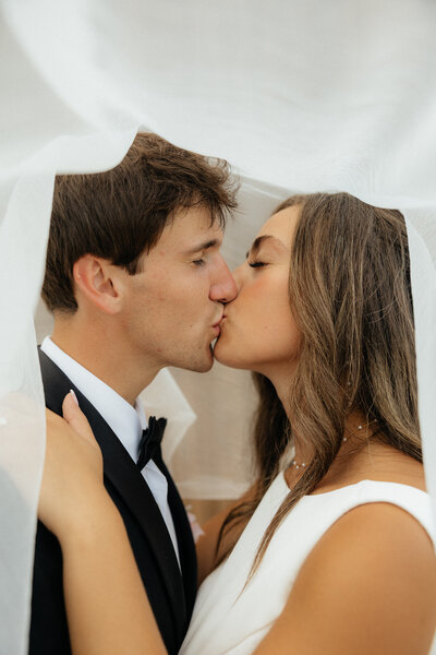 A couple kissing under the veil.