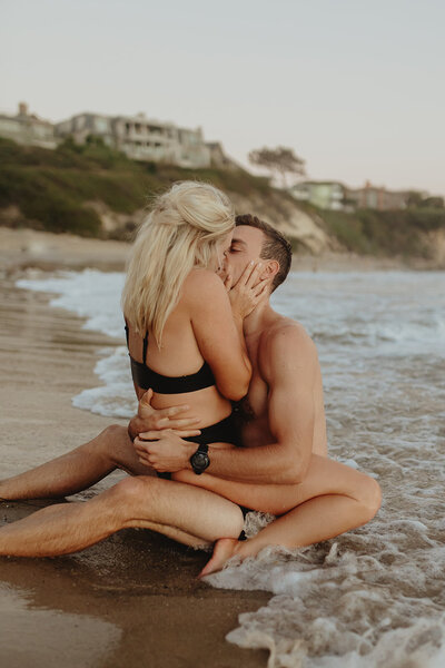 Intimate kissing photo of a couple in their bathing suits at an Orange County Beach