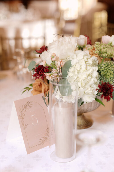 November wedding at Graylyn Estate, designed and planned by Charming Carolina — close-up of a floral centerpiece with muted greenery and a sand-colored taper candle.