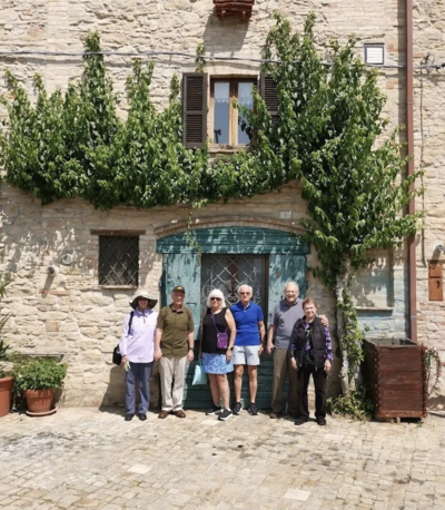 a small group of people poses in front of an old building On the Italian on Tour’s 10 day Epicurean Journey trip through Italy