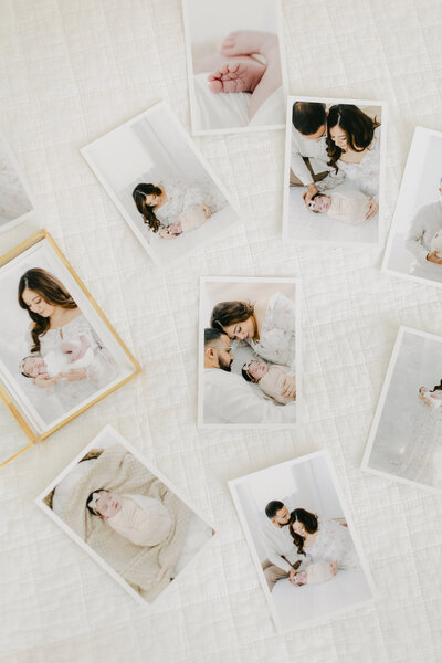 prints from South Jersey newborn photography session laid out across bed