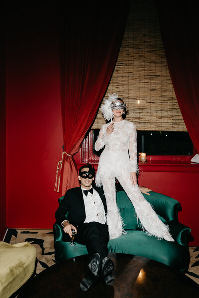 Bride seated on a vintage red chair in moody studio setting