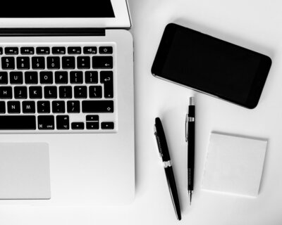 Pens and cell phone next to a laptop