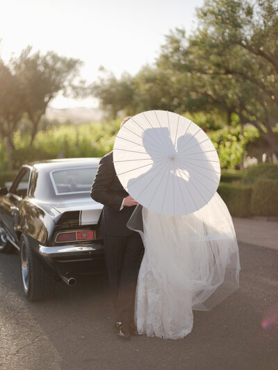 A black and white image of a couple in wedding dress runs through the vineyards
