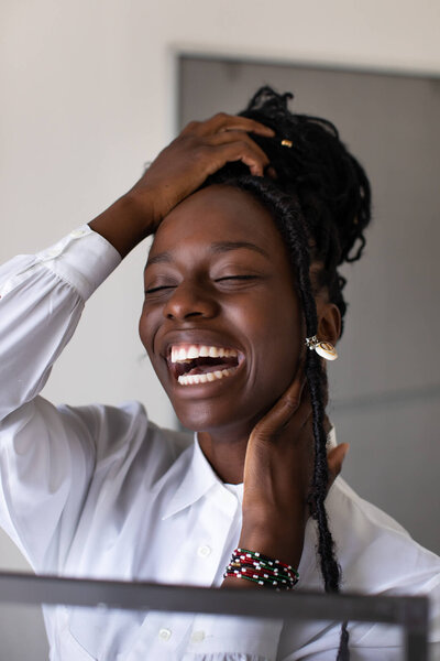 A stunning studio portrait of a beautiful young black woman laughing and wearing braids and a white shirt. Captured by Branson photographer Dynae Levingston