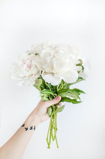 Showit web designer holding a bouquet of white flowers against a white background