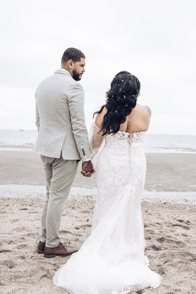bride and groom holding hands on the beach