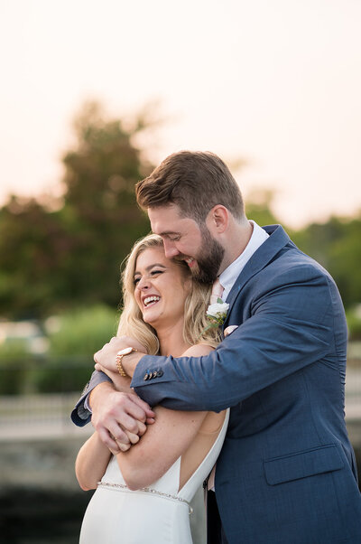 A bride and groom hugging and smiling.