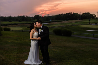 Bride and groom kiss at sunset on the golf course of Lake View Country Club