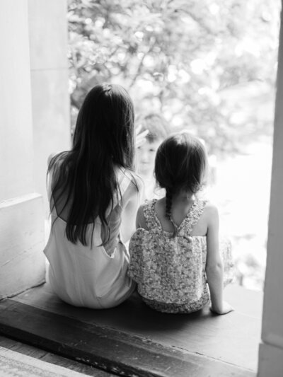 Black and White in home family photography session with two daughters sitting in doorway- captured by Amy Marie Photography 