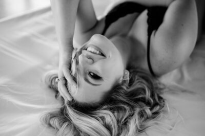 black and white little rock ar boudoir photography of woman in a black lingerie set smiling at the camera