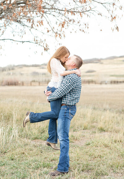Chad lifting Jayd into a kiss. Fall leaves arch above them.