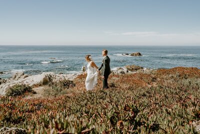 bride and groom walk out to look at carmel river state beach