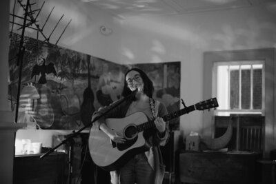 Woman smiles and sings into a microphone at Hillcrest Coffee