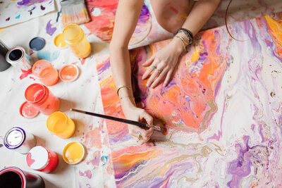 Close-up of Courtney Claire Beglin adding detail to a colorful abstract art piece
