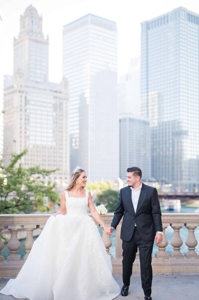 Bride and groom holding hands and walking together at the Wrigley building for their downtown Chicago wedding photos