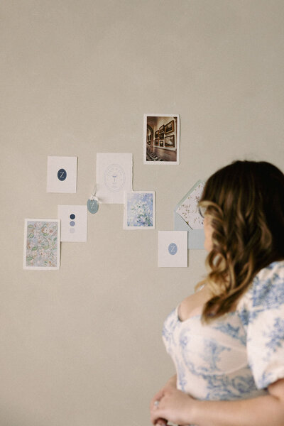 Wedding planner, Zelie & Co., looking at wedding invitation suite flat lay that has been put up on the wall