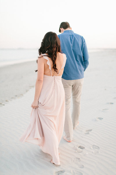 man and woman walking on the beach during destination beach engagement session