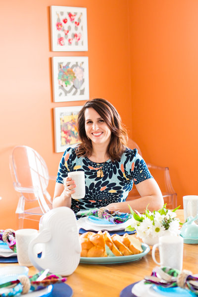 Brand photography session with home organizer in bright floral dress in an orange room