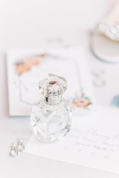 Perfume bottle sitting on top of wedding invitation