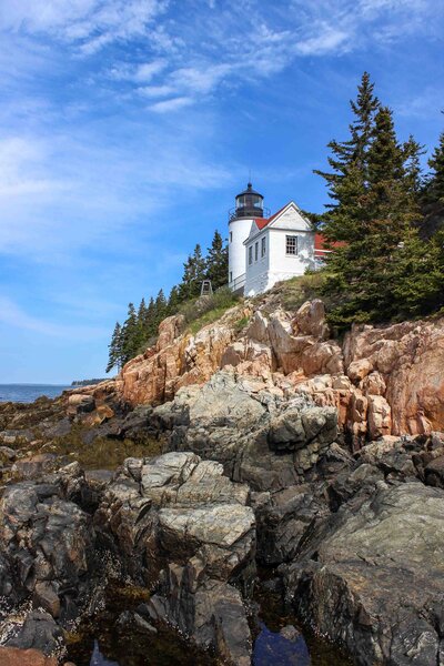 Bass Harbor Head Lighthouse perched on rugged granite cliffs, surrounded by evergreen trees in Maine ©Stephanie Dosch | theViatrix Custom Itinerary