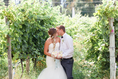 Blonde bride kissing her groom at Summer Hill Winery for their wedding day in Kelowna, BC.
