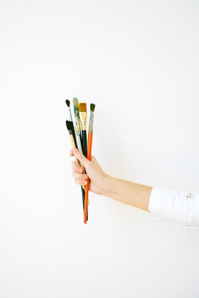 Showit web designer holding paint brushes against a white background