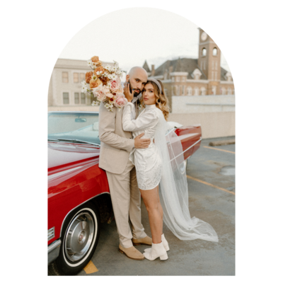 man and woman holding each other by red vintage car