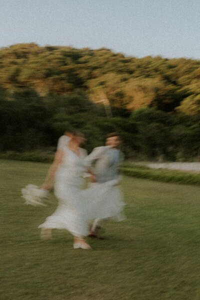 A candid grainy image of a bride and groom in COffs Harbour running towards the beach after their wedding, shot with intentional blur