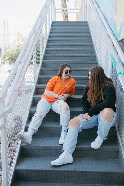 Two friends sitting on a staircase chatting.