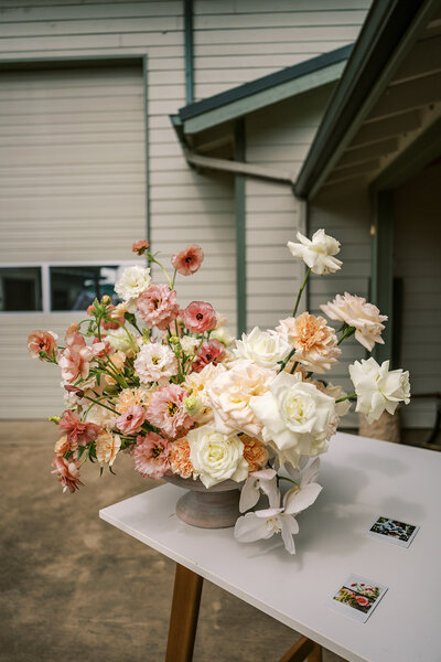 Close up photo of spring wedding flowers placed on a dinner table. The flowers are the main focus. The flower colors are peach,