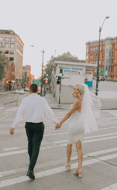 bride and groom holding hands while crossing the crosswalk after getting eloped