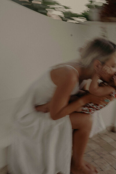 motion blur photo of person wearing white dress kissing her baby