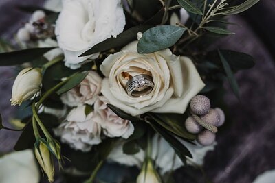 wedding rings nestled inside a gray rose - gray and white bridal bouquet with wedding rings