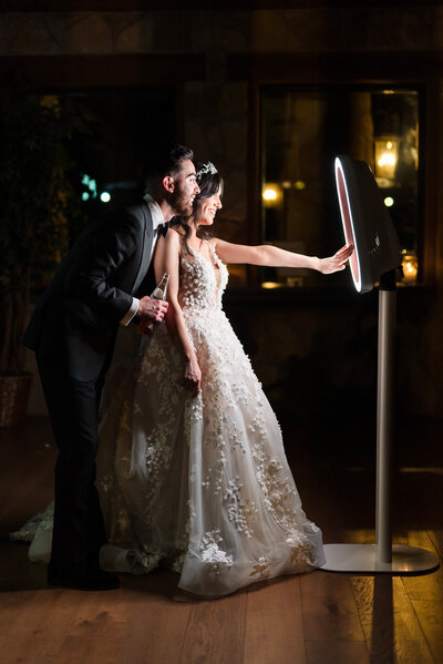 A joyful bride and groom pose in front of a mirror