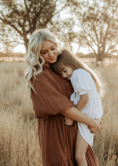 A mother and daughter share a beautiful cuddle in a golden field in Perth