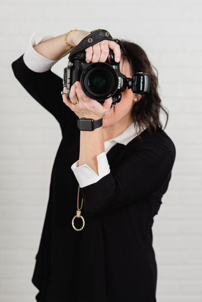 photographer dressed in black holding camera up to face