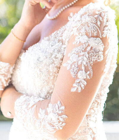 Close up shot of a white wedding dress with lace and gems
